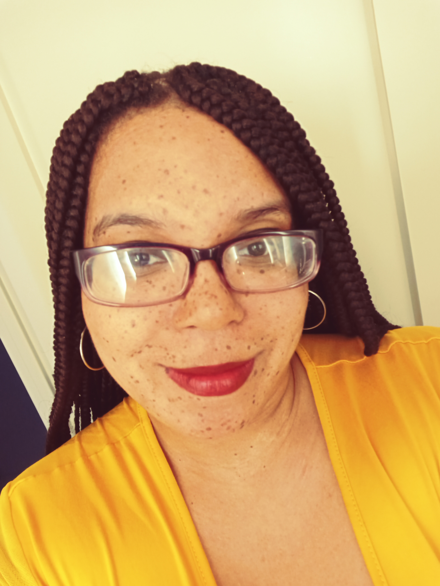 Freckled woman with glasses and braids, smiling
